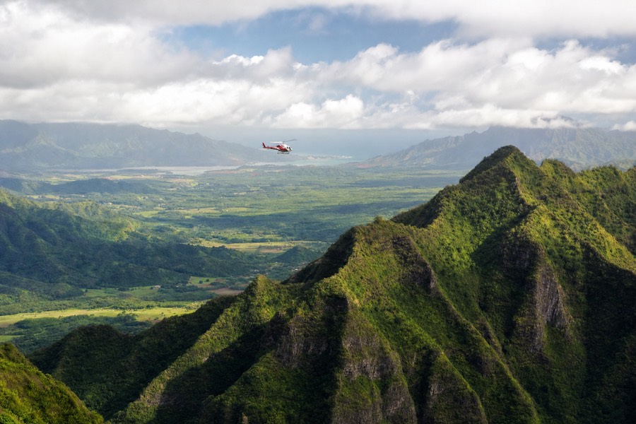 A tour helicopter banking over Kauai's green interior ridges near Lihue