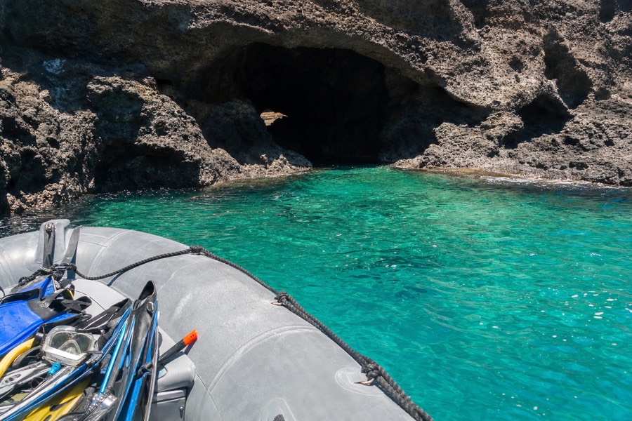 A zodiac boat near a sea cave along Kauai's sunny south shore