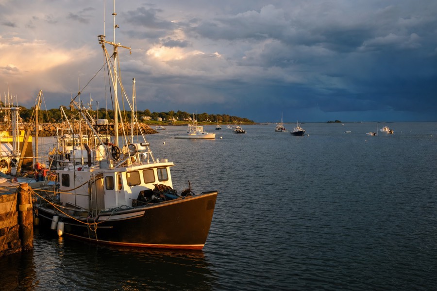 Distant storm clouds building over the ocean horizon beyond a calm Kauai harbor