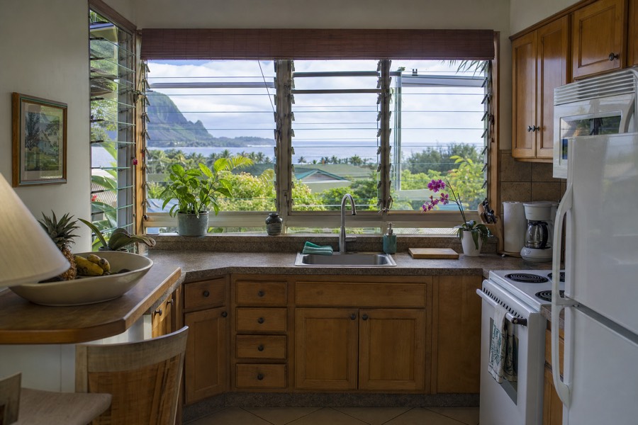 Condo kitchen with open windows overlooking the Kauai coastline and ocean in the distance