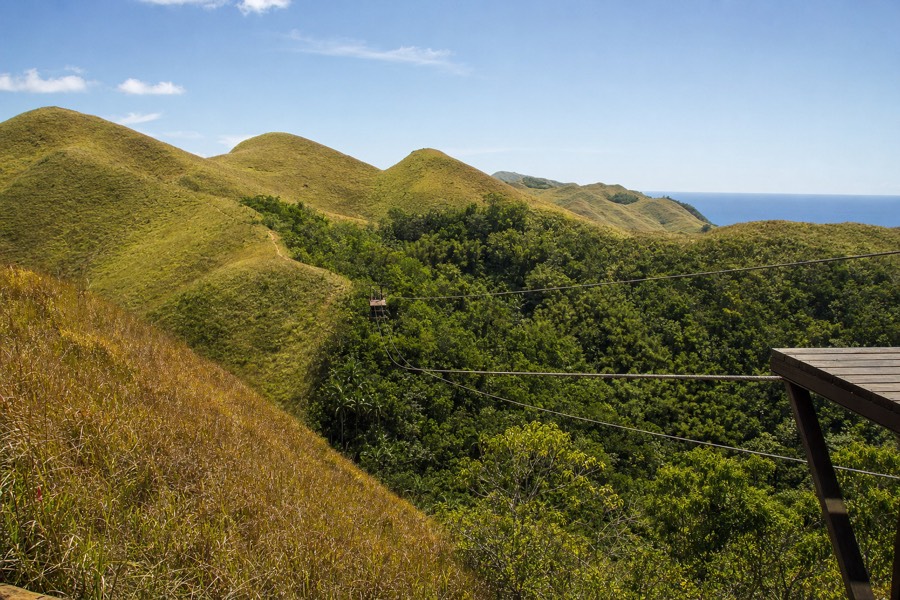 Dry grassy hills above a zipline canyon on Kauai's south side under clear afternoon sun