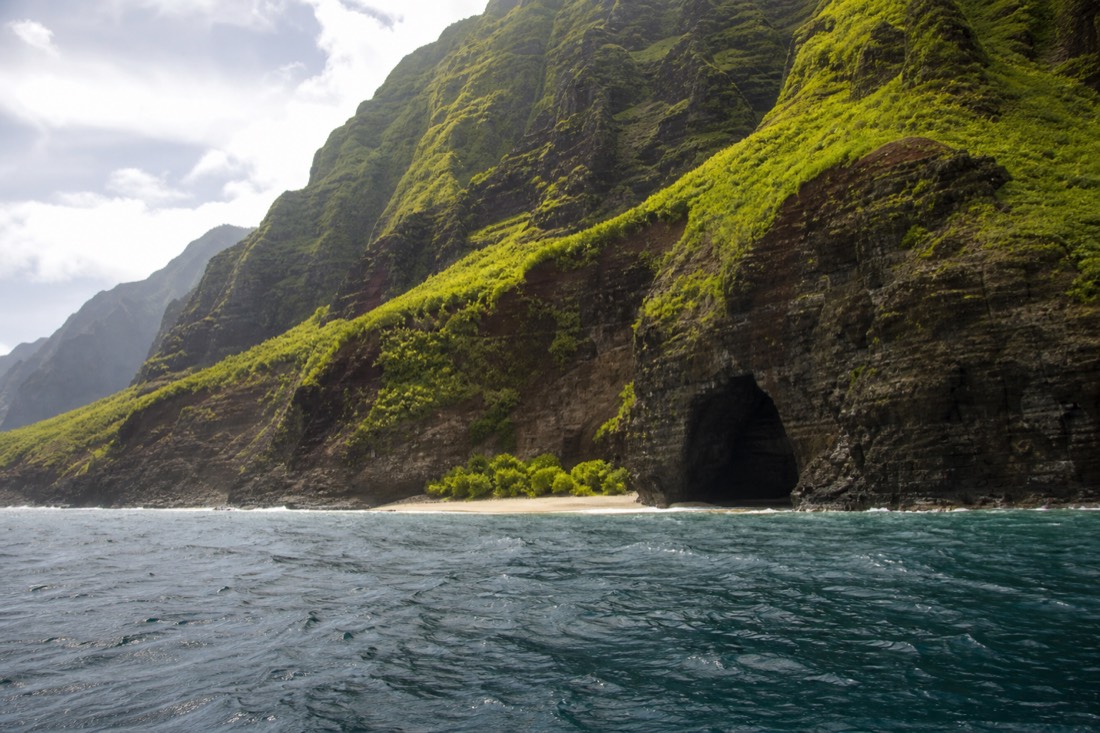 Na Pali Coast sea cliffs and a hidden beach seen from the water on a Kauai boat tour
