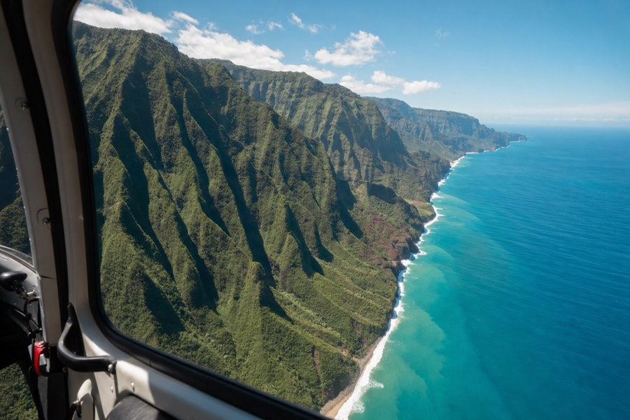 Aerial view of Kauai's Na Pali Coast cliffs and turquoise water from a sightseeing helicopter